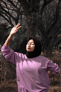 Full length of young woman standing on tree trunk