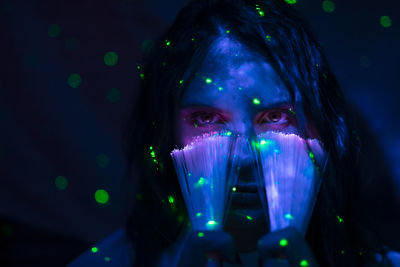 Close-up portrait of young woman by illuminate lights