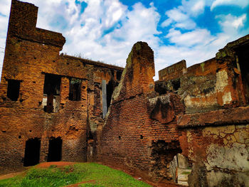 Low angle view of old building against cloudy sky