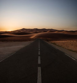 Empty road against sky during sunset