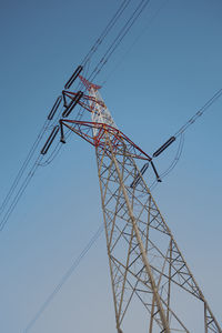 Low angle view of electricity pylon against clear blue sky