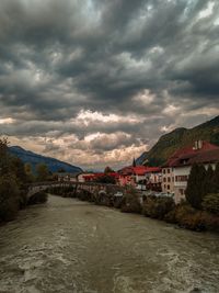 River amidst buildings against cloudy sky