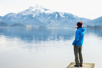 Man standing on pier over lake against mountains