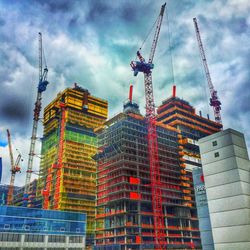 Low angle view of crane against cloudy sky