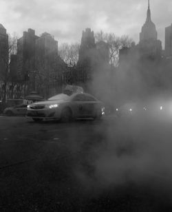 Cars on city buildings against cloudy sky