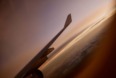 Airplane flying in sky at sunset