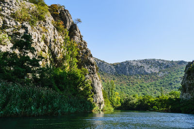 Scenic view of river by mountains against clear sky