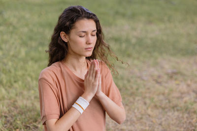 Woman with curly hair meditates in a park. yoga and meditation for mental and physical health