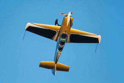 Low angle view of airplane flying against clear blue sky