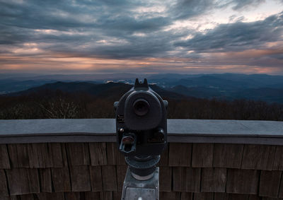Coin-operated binoculars against sky during sunset