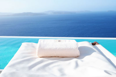 Close-up of towel on lounge chair at infinity pool against sea