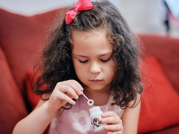 Young girl is blowing up soap bubbles in the living room