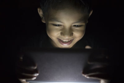 Boy using digital tablet in darkroom