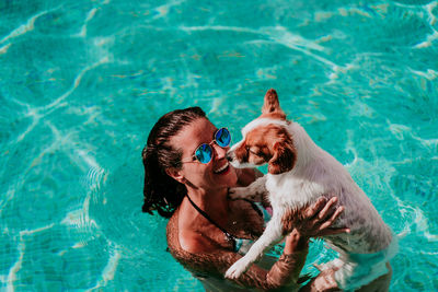 Low section of person with dog on swimming pool