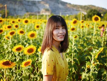 Portrait of smiling woman standing on yellow flowering plants