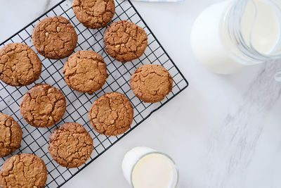 Top view delicious homemade cookies on a drying rack and a glass of milk