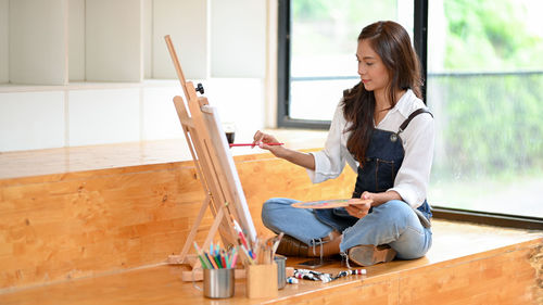 Side view of woman sitting on wooden floor