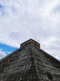 Low angle view of temple of kukulkan against cloudy sky