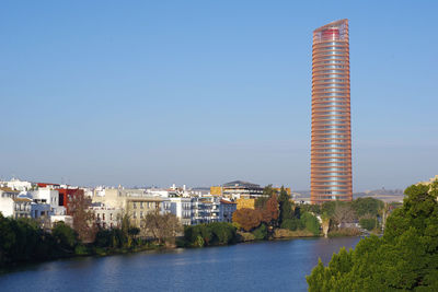 River by buildings against clear blue sky