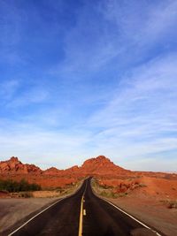 Empty country road amidst rock formations against sky
