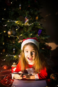 Cute girl lying down by illuminated christmas tree