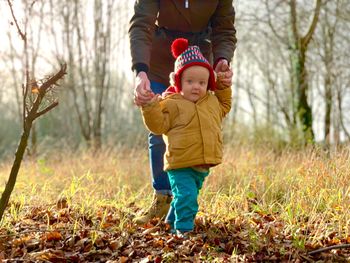 Low section of mother holding cute baby boys on field