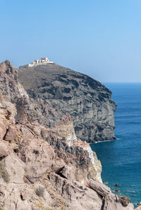 Rock formations by sea against clear blue sky