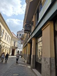 People walking on street amidst buildings in city