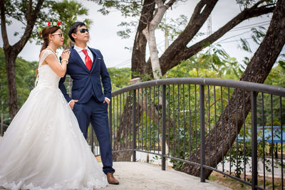 Happy couple with arms outstretched against plants