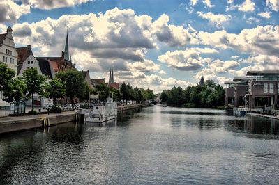 River by buildings in city against sky