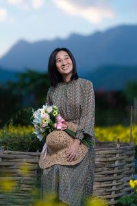 Portrait of smiling woman standing against mountain