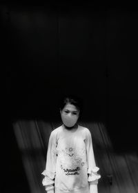 Portrait of young woman standing against wall