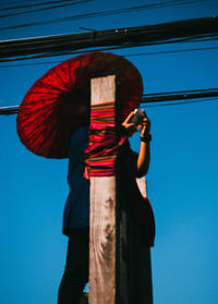 Low angle view of woman standing against blue sky