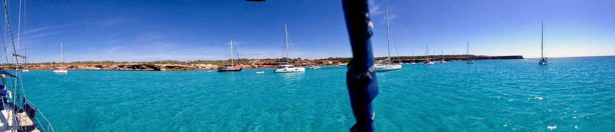 Sailboats in sea against clear blue sky