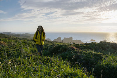 Asian girl hiking along the coast in spring during the sunset