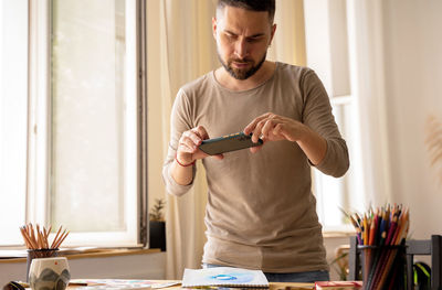 Young man using mobile phone while sitting on table