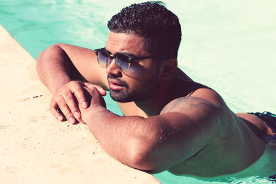 Full length of shirtless young man in swimming pool