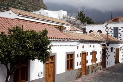 Houses by street against cloudy sky