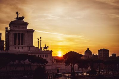 Statue in city at sunset