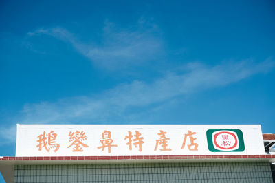 Low angle view of sign against blue sky