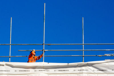 Man working on boat against blue sky