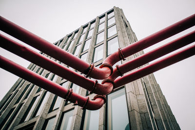 Low angle view of pipes and building against clear sky in city