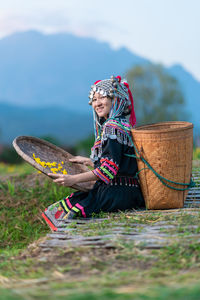 Woman wearing hat sitting on wicker basket