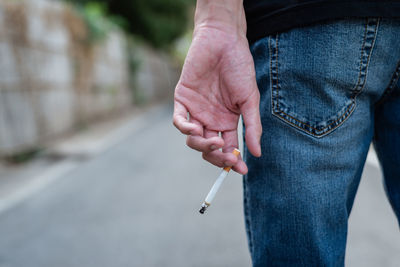 Midsection of person holding cigarette