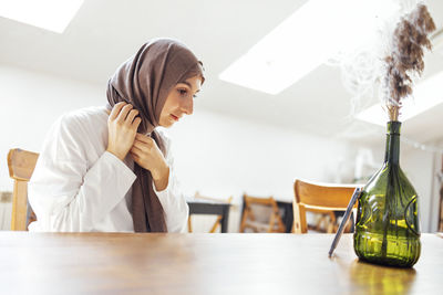 Portrait of young woman using mobile phone at table