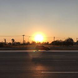 Cars on street against clear sky during sunset