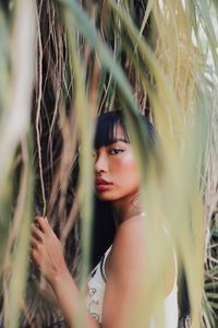 Portrait of young woman standing against plants