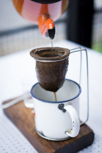 Tea pouring in mug on table