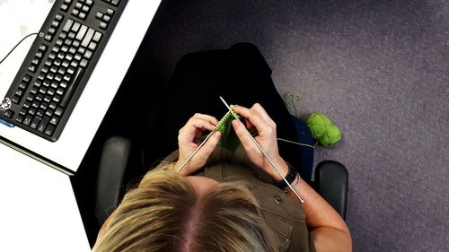 High angle view woman knitting while sitting on chair