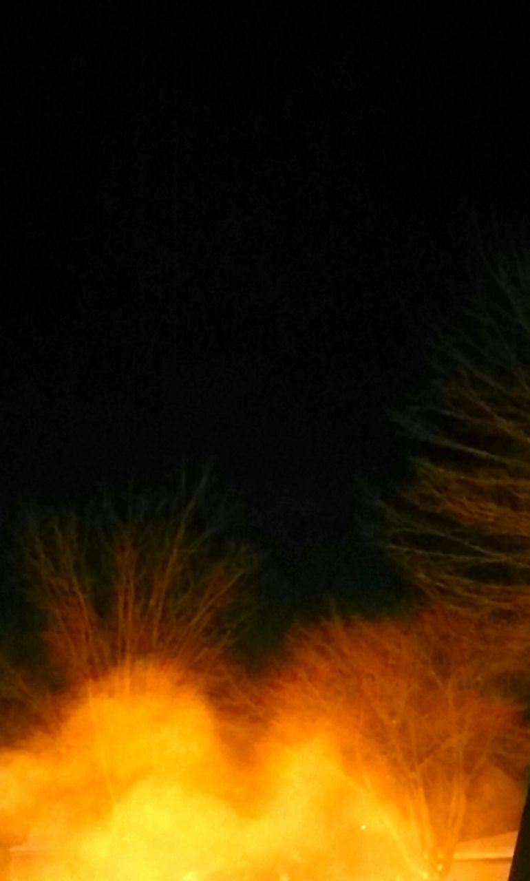 DEFOCUSED IMAGE OF ILLUMINATED LIGHTS AGAINST BLACK SKY